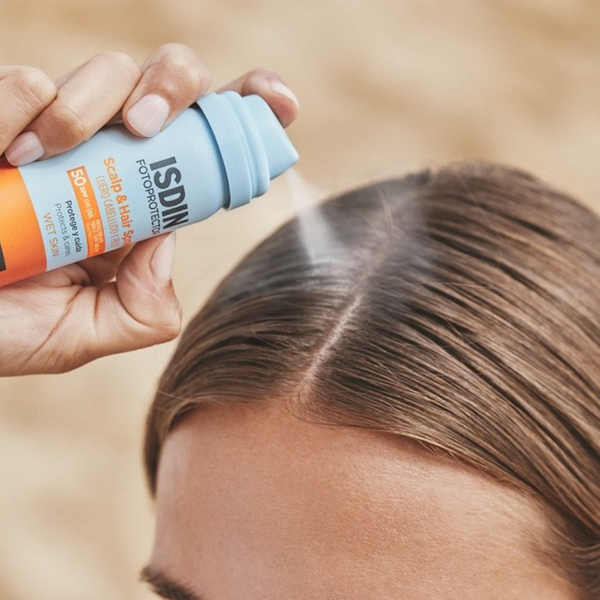 Aplicación del Scalp & Hair Spray SPF 50 de ISDIN sobre la raya del pelo