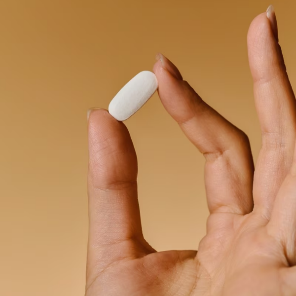 Comprimido de Solgar Piel, Uñas y Cabello con Biotina sostenido entre dos dedos