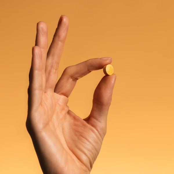 Comprimido de Solgar Vitamina B-Complex sostenido entre dos dedos