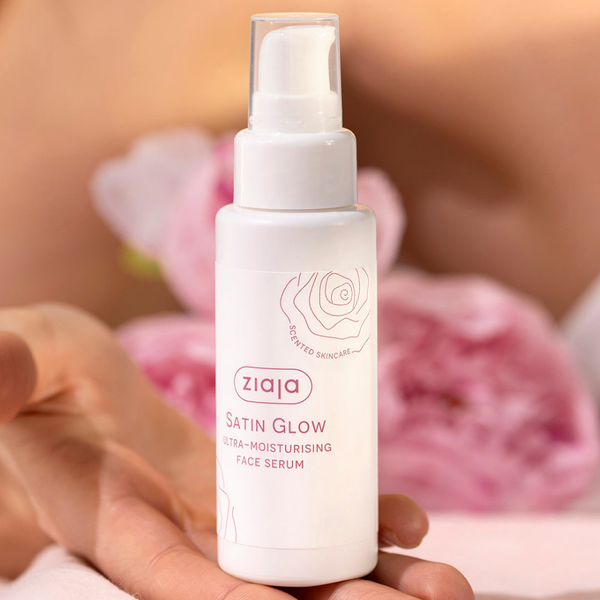 Sérum facial Ziaja Satin Glow sostenido en la mano entre flores
