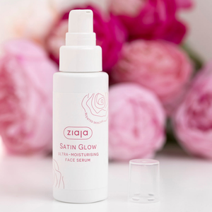 Sérum facial Ziaja Satin Glow abierto junto a peonías rosas